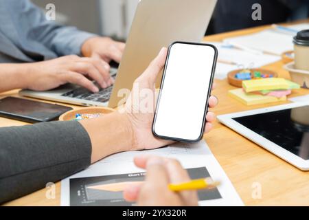 Phone with isolate screen on multicultural professional businesspeople hand while working together on research plan in boardroom. Stock Photo