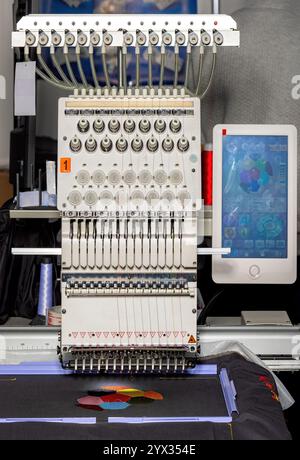 Intricate embroidery machine in action creating colorful designs in a workshop setting Stock Photo