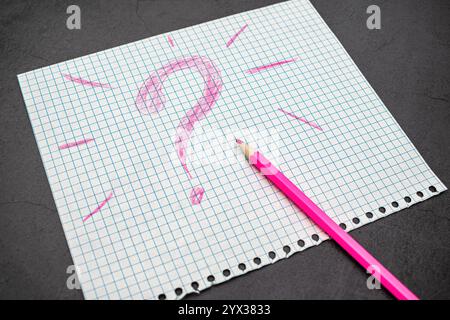 Question mark drawn with pink pencil on a piece of paper Stock Photo