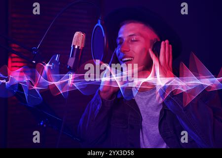 Vocalist with headphones singing into microphone in professional record studio. Sound waves Stock Photo