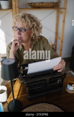 Businesswoman holding a piece of paper above a typewriter closeu Stock Photo