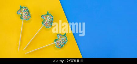 blue lollipops in the shape of unicorns on a yellow background. Stock Photo