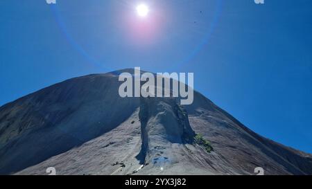 The monumental Blue Stone with the "Lizard" trying to climb it dramatically against a pristine, cloudless blue sky Stock Photo