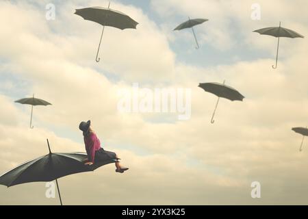 woman sitting on a flying umbrella in the sky looking at other umbrellas, abstract concept Stock Photo