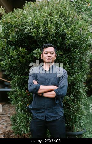 A Southeast Asian man crossing his arms, exuding confidence and contemplation. Perfect for lifestyle, portrait, or conceptual projects showcasing atti Stock Photo