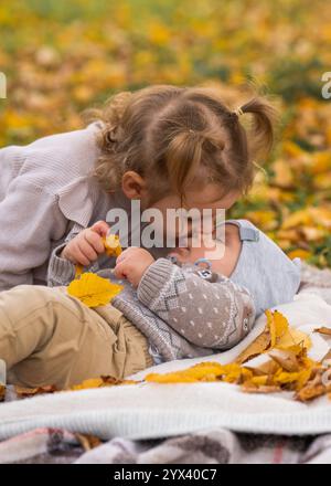 Cute brother and sister in the fall park. Girl 3 years old gently kissing her brother's boy. Love. Family. Happy childhood Stock Photo