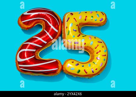 two foil balloons of different colors and patterns forming the number 25 on a blue background Stock Photo
