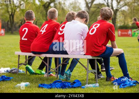 Kids in the Sports Team on Substitute Bench. Young Football Players. Young Soccer Team Sitting on Bench. Soccer Match For Children. Young Boys Playing Stock Photo