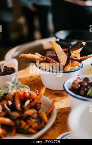 A table with a variety of food, including french fries, and a bowl of sauce. Scene is casual and inviting, as it is a meal shared among friends or fam Stock Photo