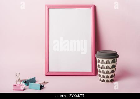 White frame with pink border paper clips coffee disposable cup against pink background Stock Photo