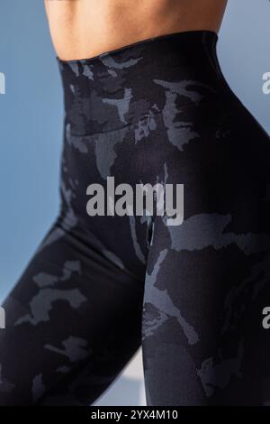 Close-up of a woman wearing black camouflage leggings, highlighting the comfortable fit and stylish design. Ideal for fitness, yoga, or activewear Stock Photo
