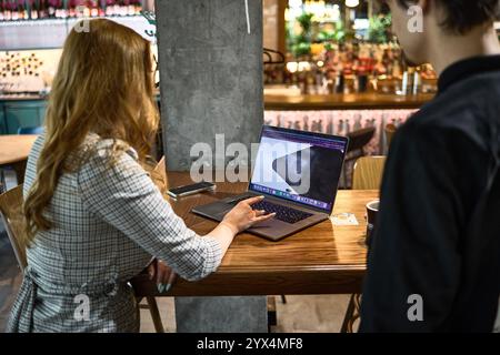 People in cafe having collaborative work session discussing project on laptop while enjoying coffee creative thinking concept Stock Photo