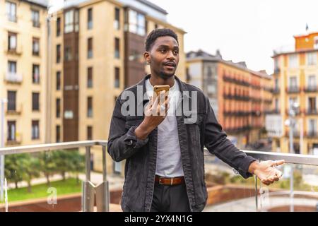 African man sending a voice message using mobile phone in the city Stock Photo