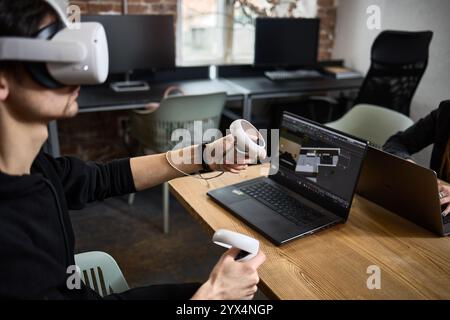 Individual wearing VR headset with hand controllers in a contemporary office setting for an engaging virtual experience concept Stock Photo