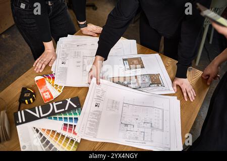 Team of architects reviewing blueprints and discussing project details at a desk, emphasizing collaboration in architecture concept Stock Photo
