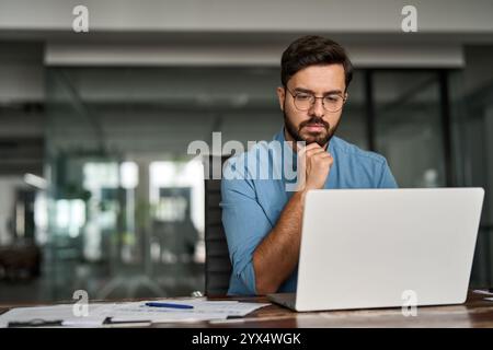 Busy young business man thinking on online investment working on laptop. Stock Photo