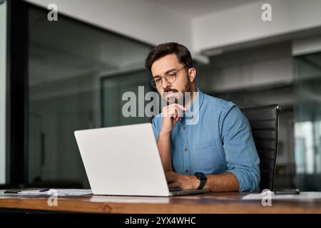 Young professional busy business man thinking looking at computer at work. Stock Photo