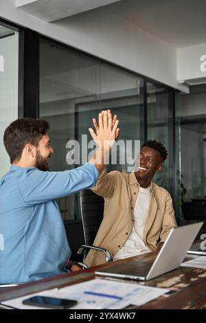 Happy diverse young business men colleagues work team partners giving high five. Stock Photo