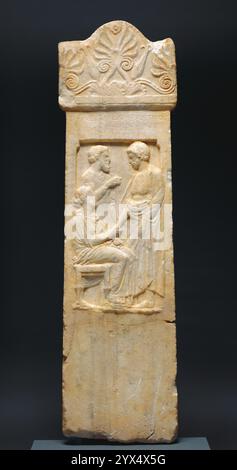 Grave Stele of Thrasynos, about 375 BC. Gravestone of Thrasynos.  Additional Info: A family group of mother, father, and son carved in a sunken relief panel decorates this Athenian grave stele or tombstone. The inscription above the relief names all the figures. Archilla, the mother, sits on a stool and shakes hands with her deceased son, Thrasynos, while Thrasonides, the father, stands in the background. The sacrificial knife in his hand and his special sleeveless garment indicate his status as a priest. In ancient Athens family connections were very important in all aspects of life, and the Stock Photo