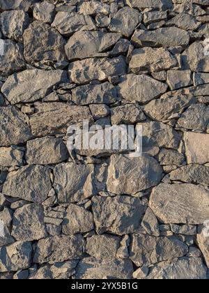 Background of a stacked stone wall of volcanic rock. Vertical shot. Stock Photo