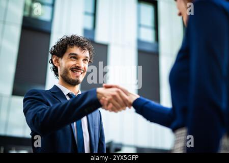 Two business partners shaking hands outside their office building, exuding trust and respect in a successful collaboration Stock Photo