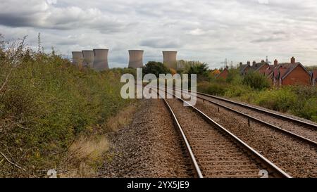 a railway track leads the viewer to five cooling towers at a power station in the distance. Located in Willington, Derbyshire Stock Photo