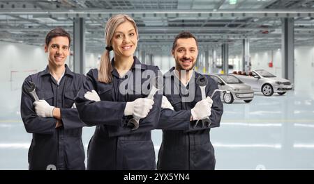 Team of car mechanics holding working tools in a car garage Stock Photo