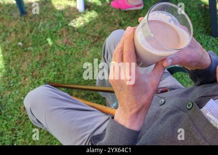 an elderly man drinking a milk shake in his garden Stock Photo