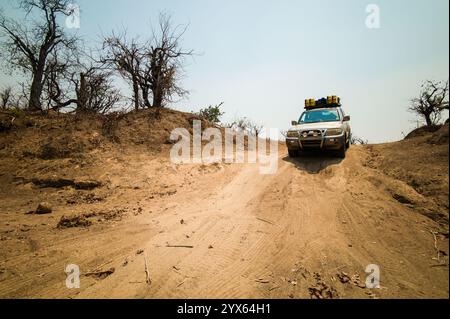 A four-wheel drive SUV drives a dirt road exploring Gonarezhou National Park, Masvingo Province, Zimbabwe, during the dry season on self-drive safari Stock Photo