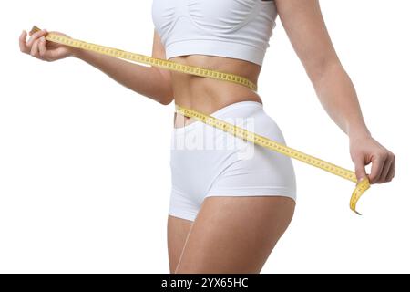 Weight loss. Woman measuring her slim waist with tape on white background, closeup Stock Photo