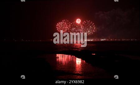 Fireworks display over a dark body of water, reflecting on the water surface. Stock Photo