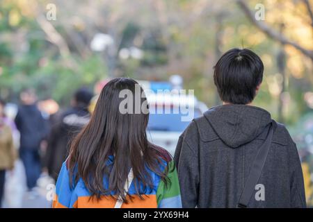 A young Chinese couple in their 20s walking on the sidewalk in Hongkou District, Shanghai, People's Republic of China, during the cold season, Decembe Stock Photo