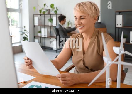 Female engineer working with wind turbine models on table in office Stock Photo