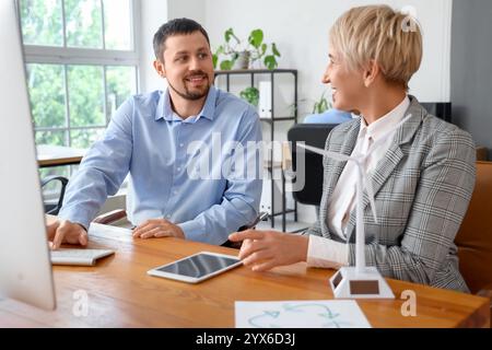 Engineers working with wind turbine model on table in office Stock Photo