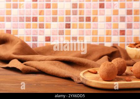 Board with tasty marzipan candies covered with cocoa powder and napkin on wooden table Stock Photo