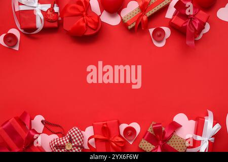 Gift boxes with paper hearts and candles on red background. Valentine's Day celebration Stock Photo