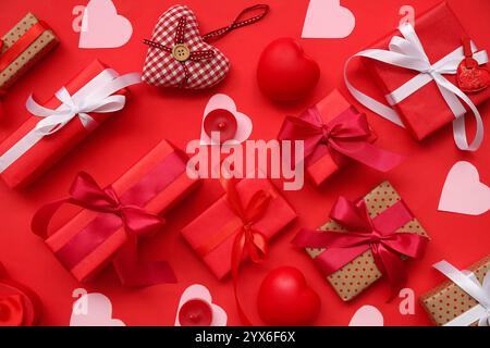 Gift boxes with paper hearts and candles on red background. Valentine's Day celebration Stock Photo