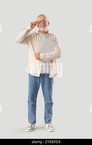 Mature programmer with laptop on light background Stock Photo