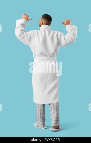 Young man in robe on blue background. Back view Stock Photo