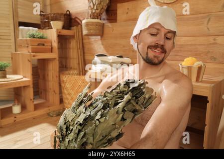 Handsome man with whisk relaxing in sauna Stock Photo