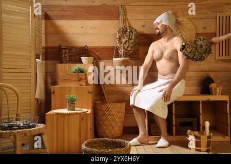 Woman beating man with whisk in sauna Stock Photo