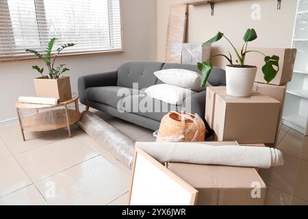 Interior of room with black sofa, table and cardboard boxes on moving day Stock Photo