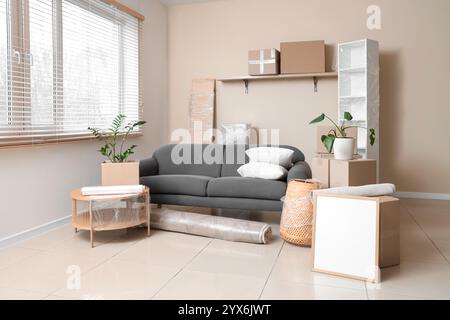 Interior of room with black sofa, table and cardboard boxes on moving day Stock Photo