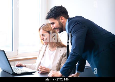 Colleagues Collaborating on Laptop in Bright Office Setting Stock Photo