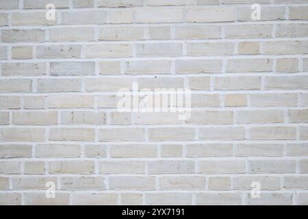 A clean and neutral light brick wall featuring evenly spaced bricks in shades of white, beige, and gray. Stock Photo