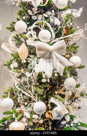 Christmas fir tree decorated with white Christmas ornaments and white and yellow lights. Stock Photo