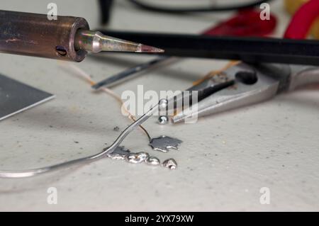 Soldering iron tip with solder and splatter on workbench Stock Photo