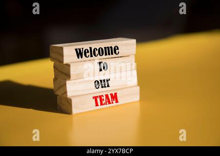 Welcome to our team symbol. Concept words Welcome to our team on wooden blocks. Beautiful yellow and blurry background. Business and Welcome to our te Stock Photo