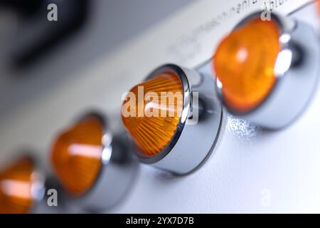 Close-up of a orange signal lamps. Close-up of a orange signal lamps in a row on a power distributor of a heating system. Analog device, electrical equipment, control panel technology. obj switchboard control light B97A8086 Stock Photo