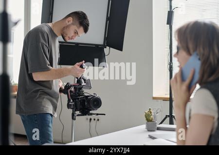 Young adult Caucasian cameraman using professional huge camera to shoot talented actress Stock Photo